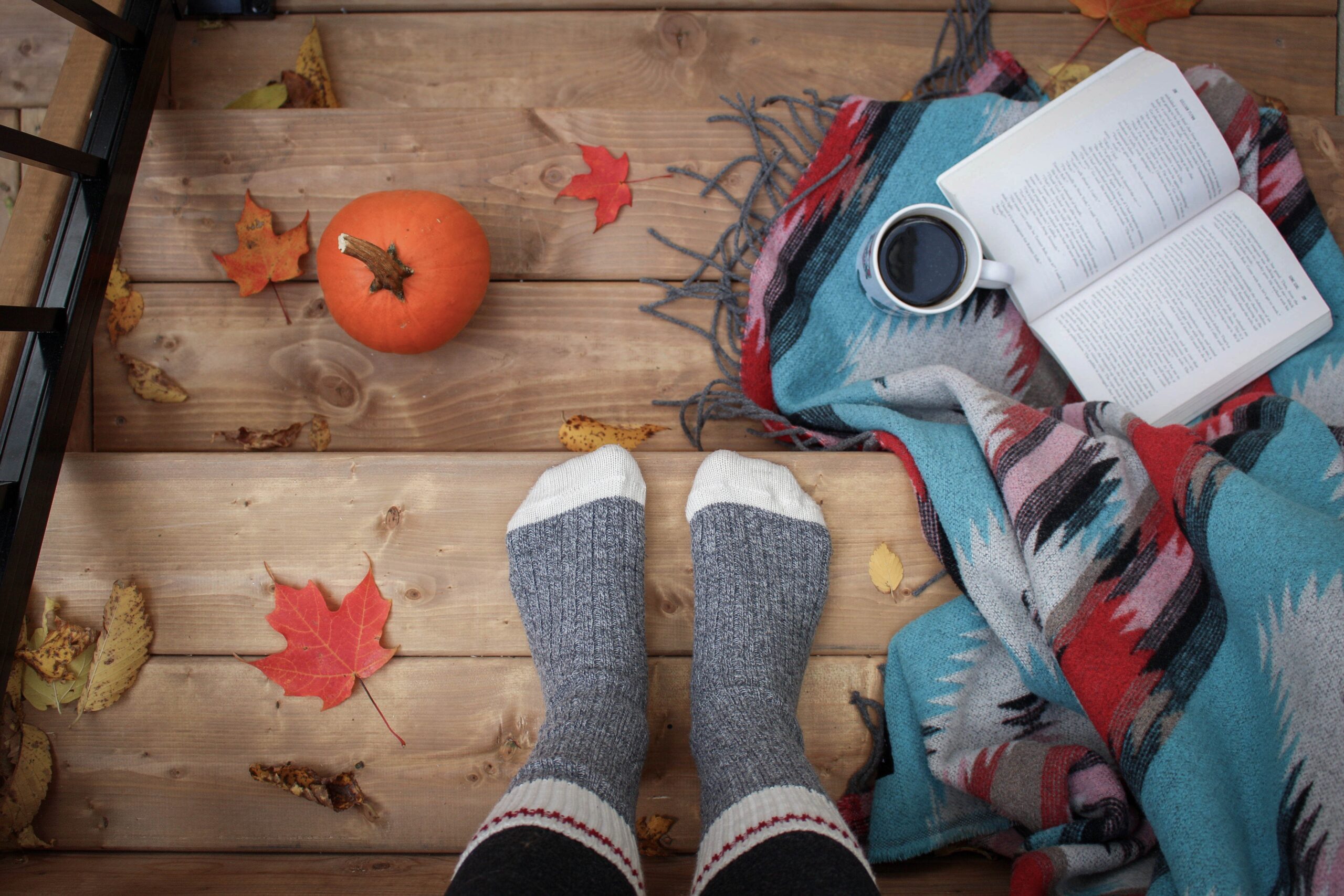 a cozy fall scene with a book, hot drink, and pumpkin