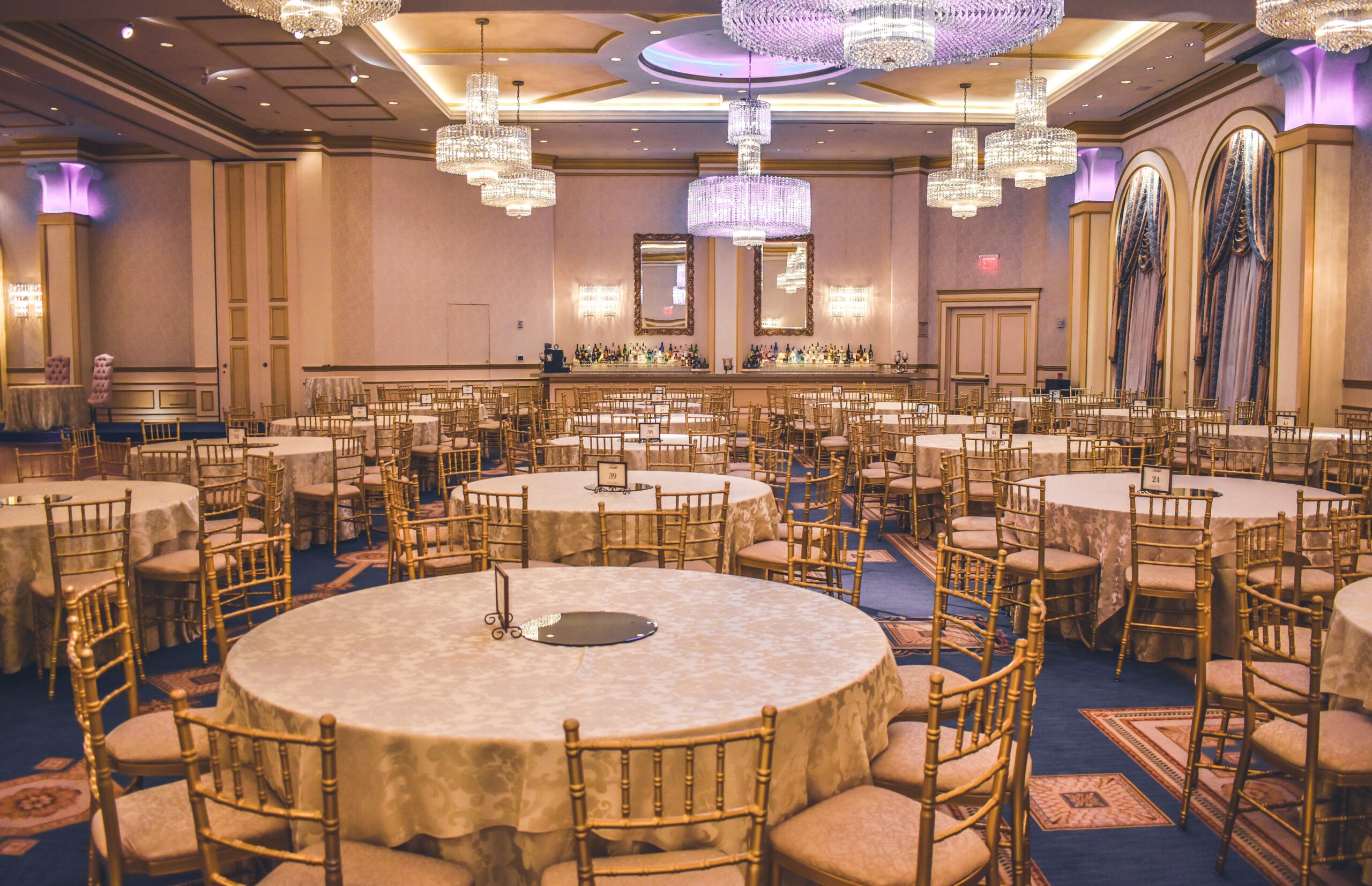 Elegant banquet room set with round tables and gold chairs prepared for a formal event with reserved seating