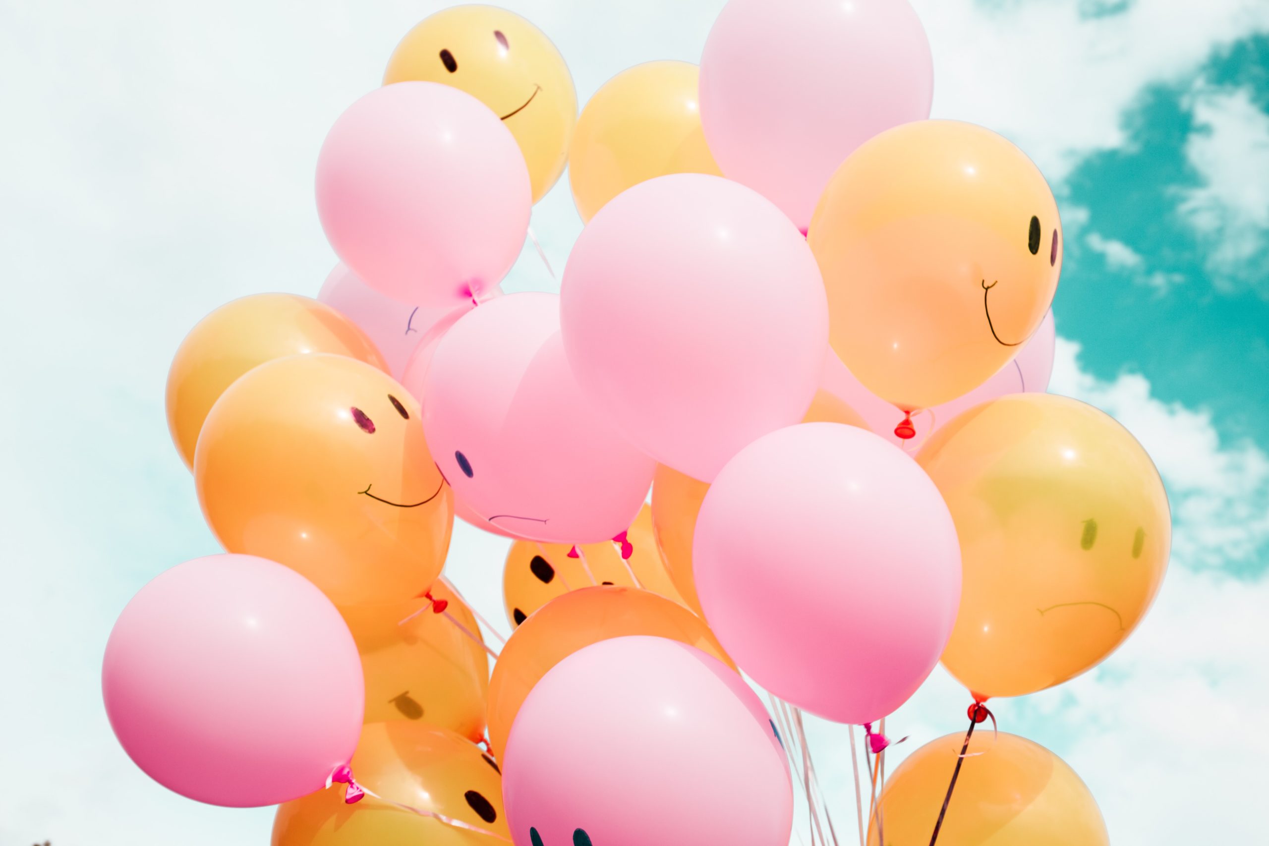 Pink and yellow balloons with expressive faces symbolising the ups and downs of social media engagement